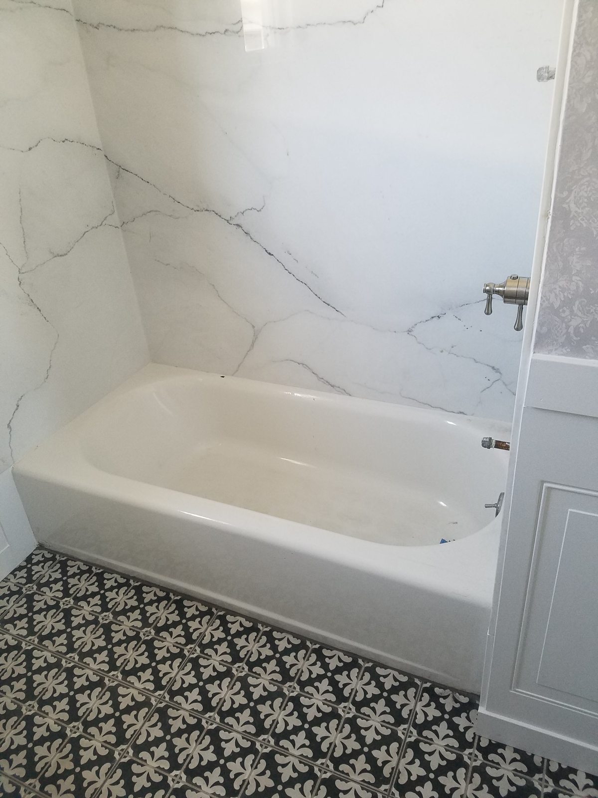 White bathtub and marble-look wall tile