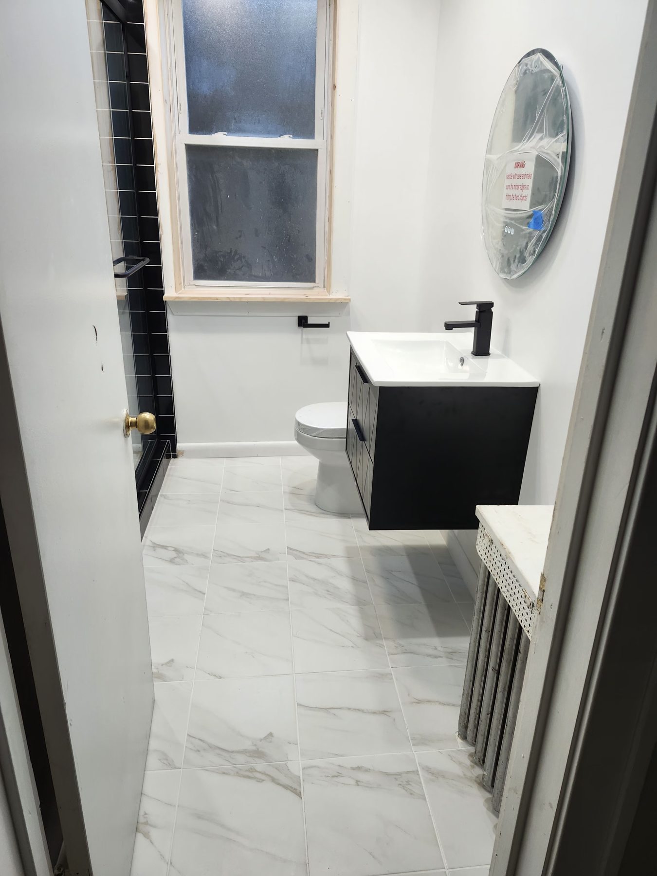 Renovated bathroom with black shower and marble-look tile